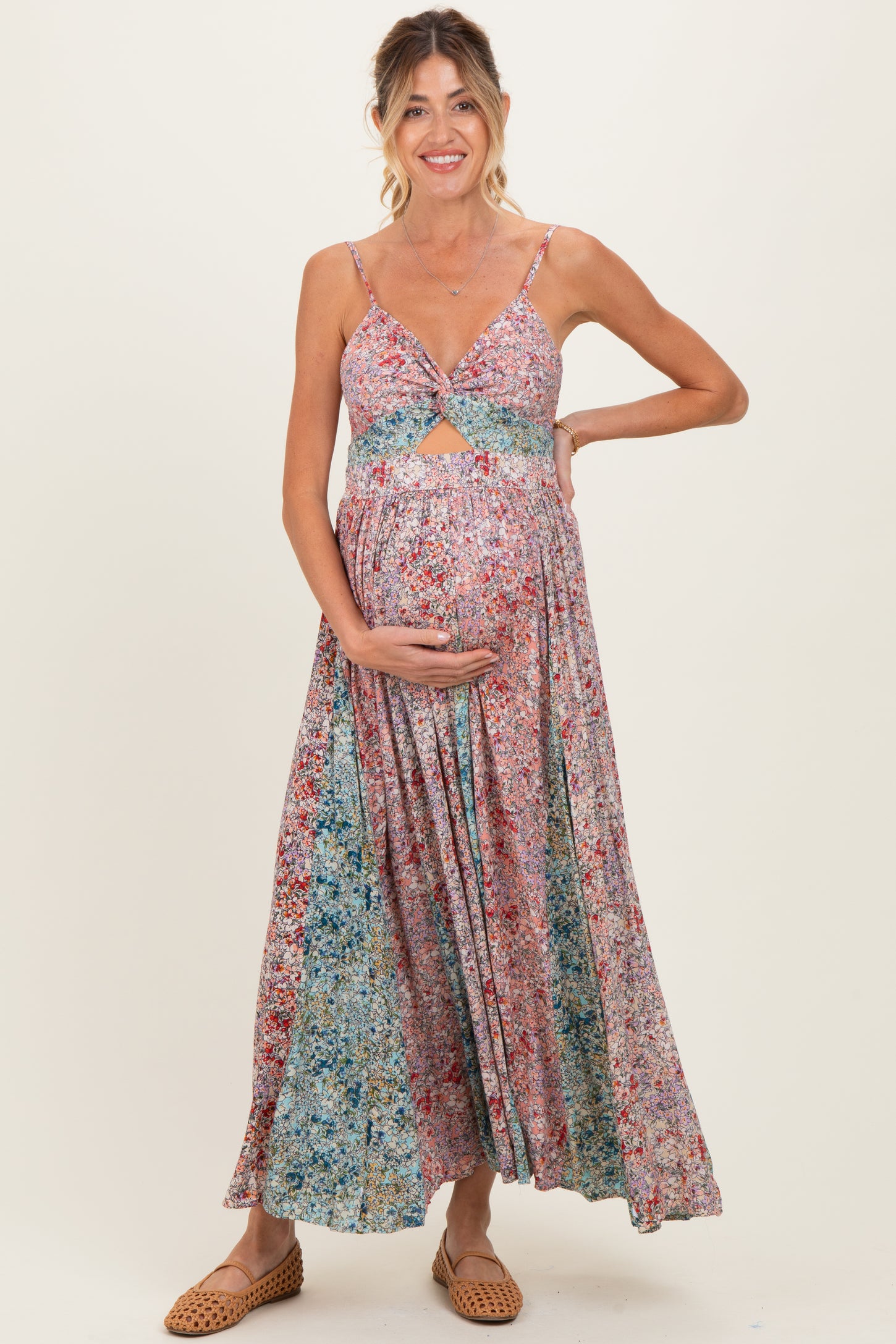 woman wearing a floral maternity maxi dress with a cutout detail and holding her baby bump