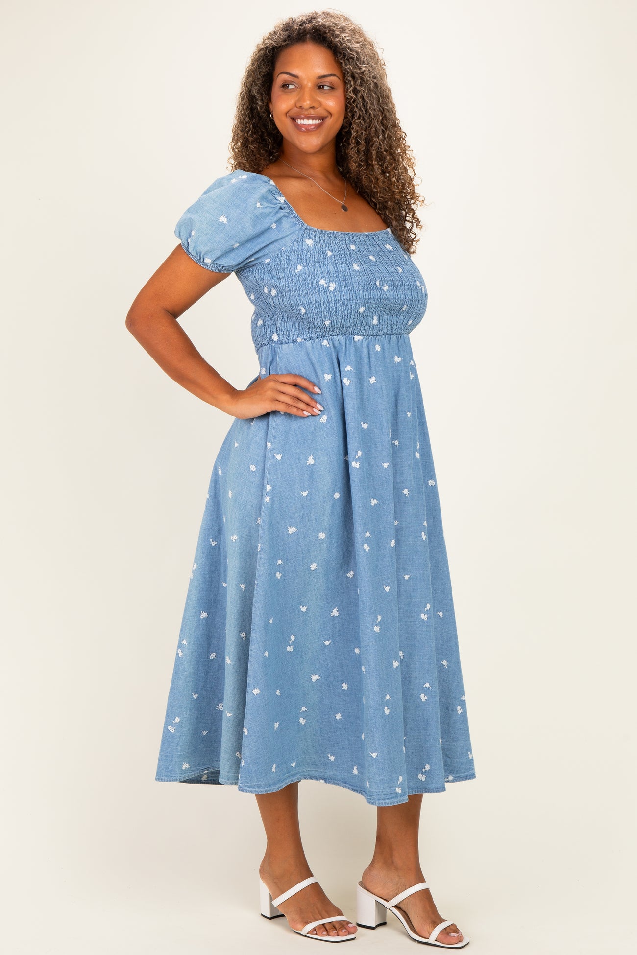 woman wearing a light blue floral print plus size midi dress with puff sleeves and a fitted bodice