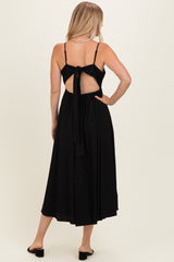 woman wearing a black midi dress with a tie-back detail and spaghetti straps, showing a bare back