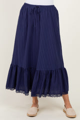 woman wearing a navy blue maxi skirt with vertical stripes and a layered lace trim at the hem