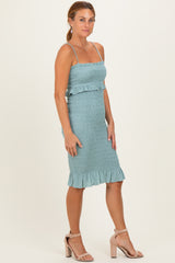 woman wearing a light blue smocked midi dress with ruffle details and thin straps