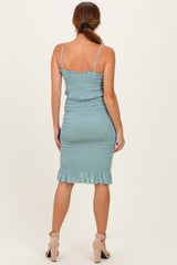 woman wearing a teal smocked bodycon dress with ruffled hem and adjustable spaghetti straps, viewed from the back