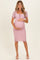 woman wearing a pink polka dot maternity dress with short puff sleeves and holding her baby bump