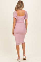 woman wearing a pink polka dot maternity dress with short puff sleeves and a fitted midi length
