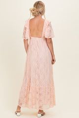 woman wearing a light pink lace maxi dress with short puff sleeves and a deep back neckline