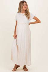 woman wearing a cream maternity maxi dress with short sleeves and an empire waist, showing her baby bump