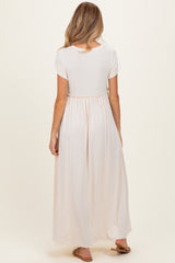 woman wearing a light pink maternity maxi dress with a gathered waist and a flowing skirt, seen from the back