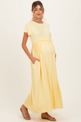 woman wearing a yellow short sleeve maternity maxi dress with pockets and a visible baby bump