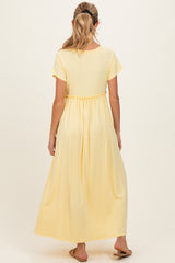 woman wearing a yellow maternity maxi dress with short sleeves and an elastic waistband, viewed from the back