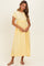 woman wearing a yellow short sleeve maxi dress with a gathered waist and flowy skirt