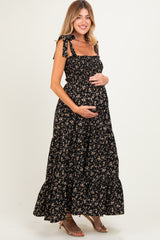 woman wearing a black floral maternity maxi dress with tie straps and holding her baby bump