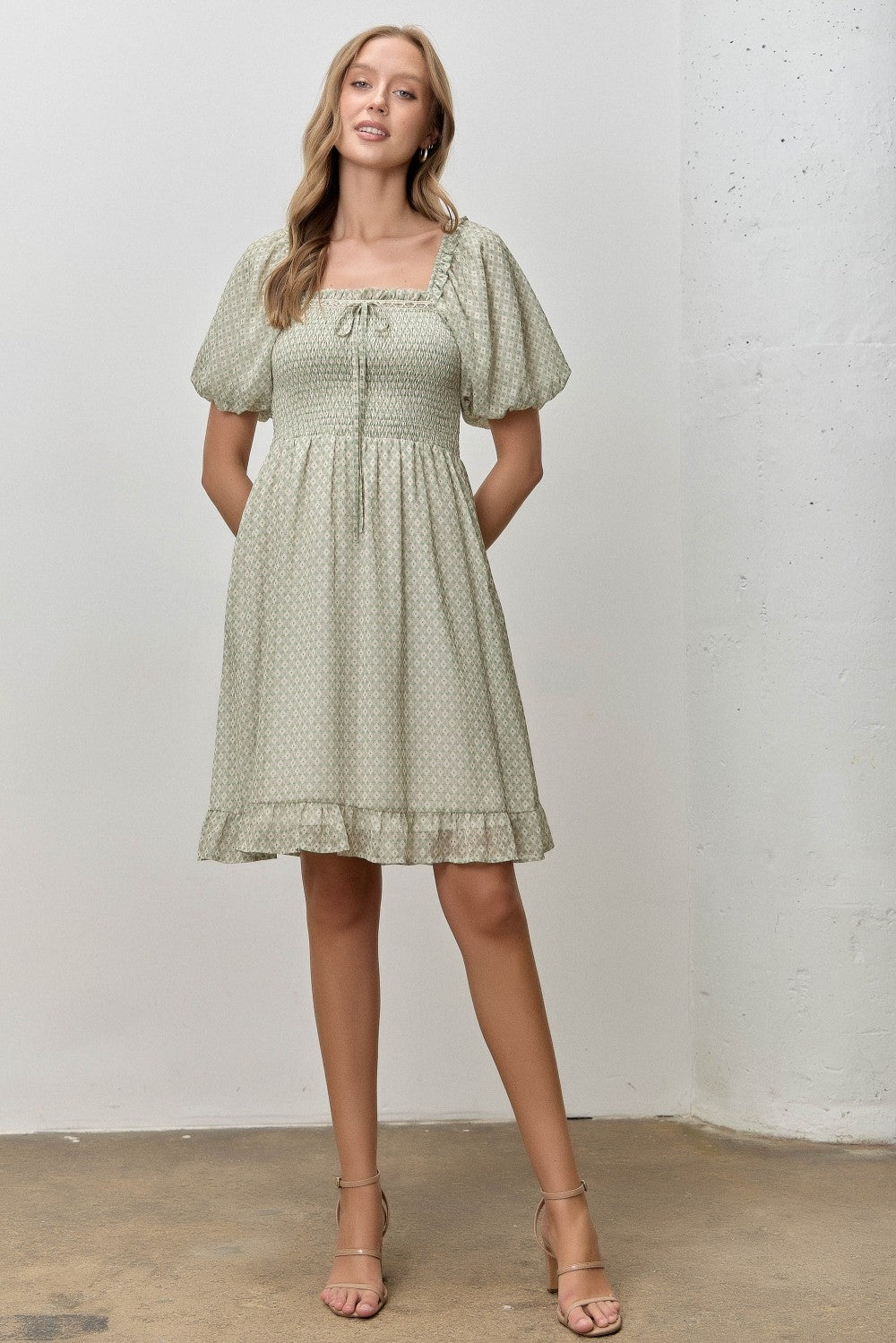 woman wearing a light green puff sleeve mini dress with a square neckline and ruffled hem