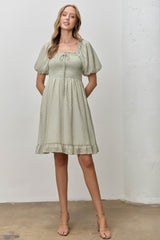 woman wearing a light green puff sleeve mini dress with a square neckline and ruffled hem