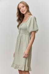 woman wearing a light green smocked puff sleeve dress with a square neckline and ruffle hem