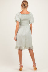 woman wearing a mint green maternity dress with puff sleeves and a ruffled hem, showing off her baby bump