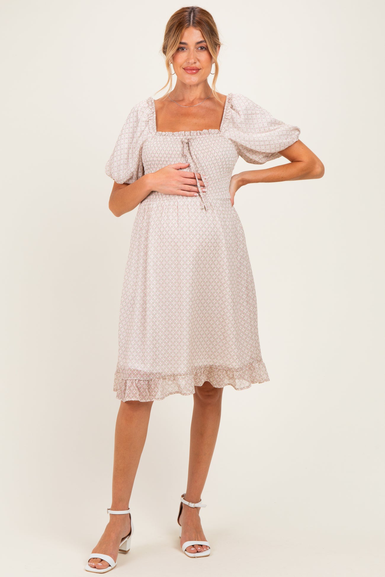 woman wearing a light pink maternity dress with puff sleeves and a square neckline, featuring a ruffled hem