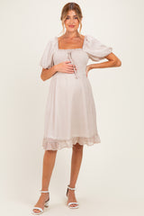 woman wearing a light pink maternity dress with puff sleeves and a square neckline, featuring a ruffled hem