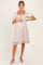 woman wearing a light pink maternity dress with puff sleeves and a square neckline, featuring a ruffled hem