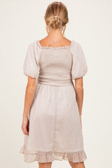 woman wearing a maternity off-white puff sleeve dress with a smocked bodice and ruffled hem, showing her back