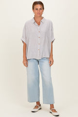 woman wearing a striped button-up shirt with short sleeves and light blue wide-leg jeans
