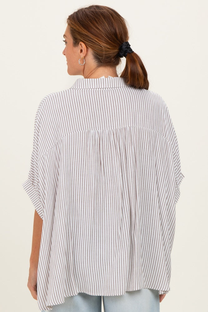 woman wearing a light gray and white striped oversized blouse with a loose fit and short sleeves