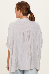 woman wearing a light gray and white striped oversized blouse with a loose fit and short sleeves