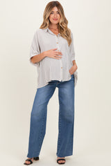 woman wearing a striped maternity button-up shirt and blue wide-leg jeans with visible baby bump