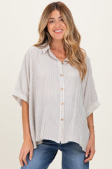woman wearing a beige and white striped maternity shirt with short sleeves and buttons, paired with blue jeans