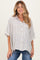 woman wearing a beige and white striped maternity shirt with short sleeves and buttons, paired with blue jeans