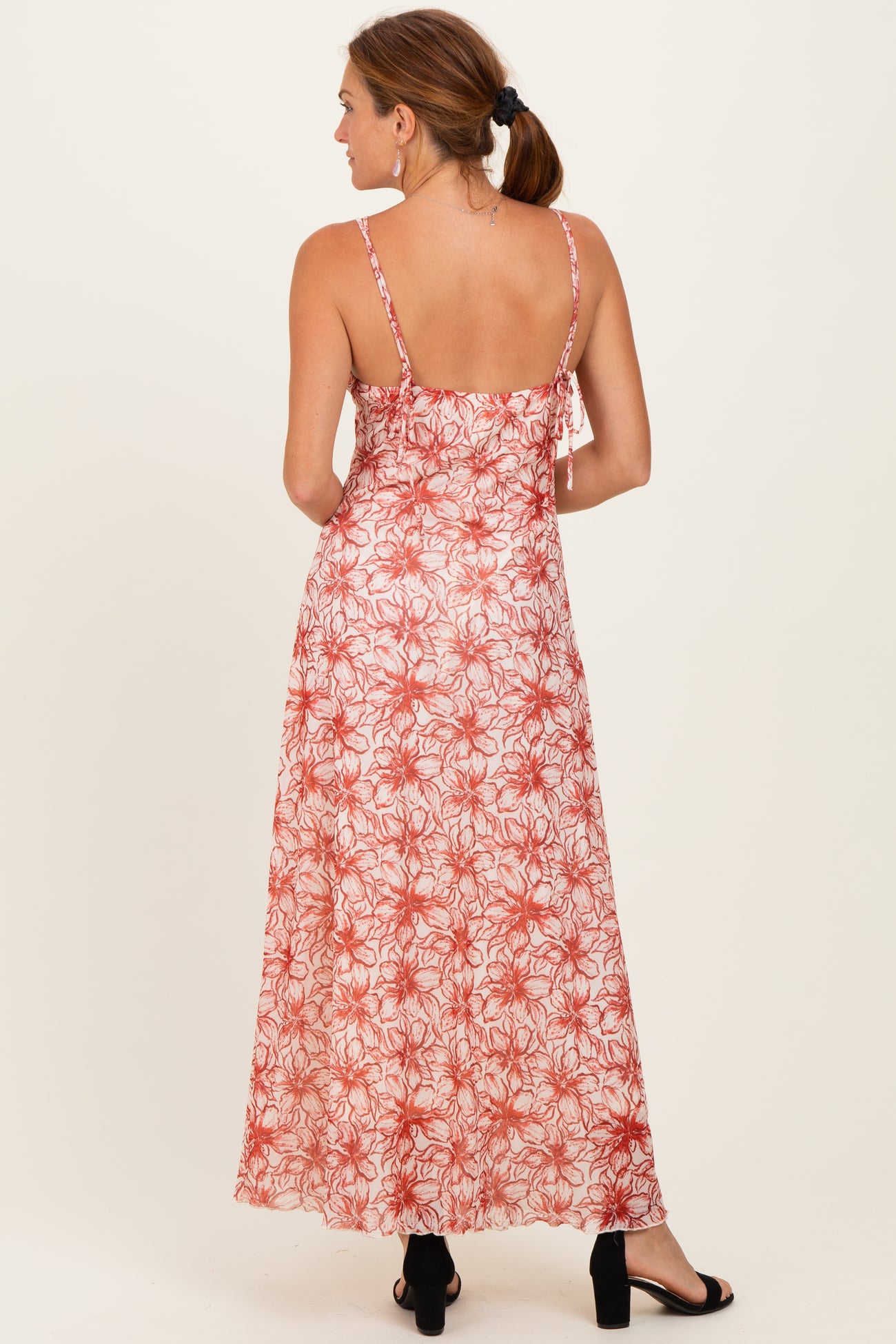 woman wearing a back view of a long floral maxi dress in red and white with adjustable straps