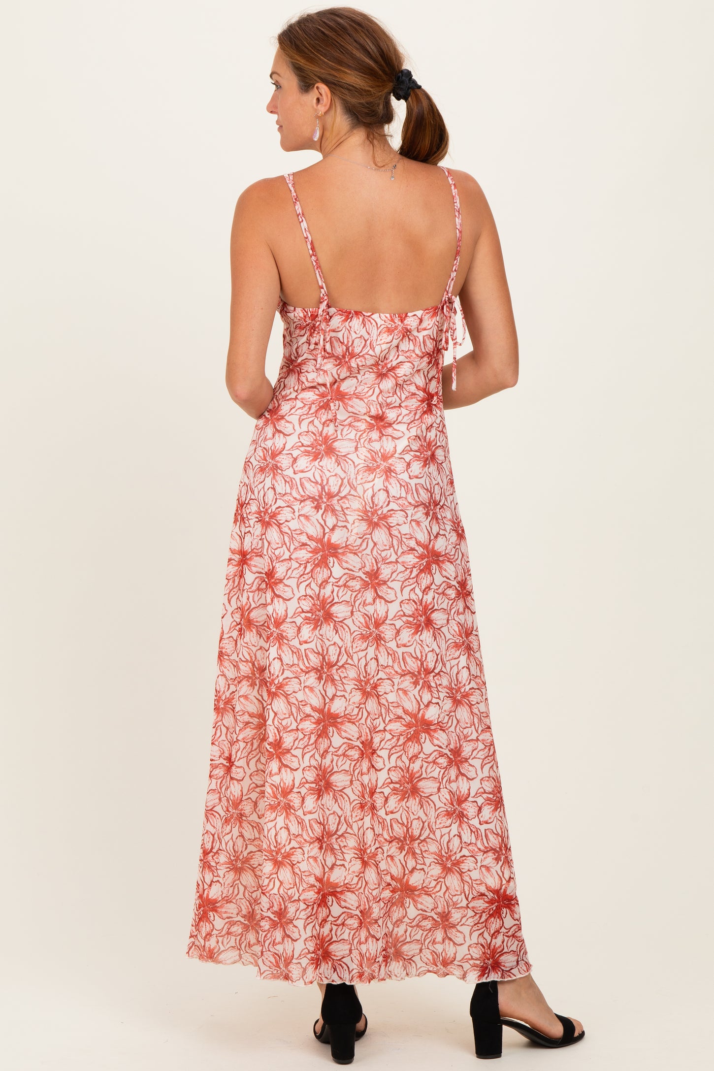 woman wearing a back view of a long floral maxi dress in red and white with adjustable straps