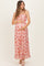 woman wearing a pink floral maternity maxi dress, holding her baby bump
