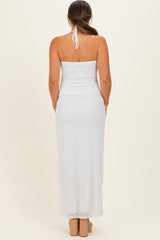 woman wearing a white fitted halter neck maternity dress with a long skirt and a ruched design