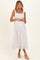 woman wearing a white floral maternity dress with adjustable straps and a cinched bodice, showing her baby bump