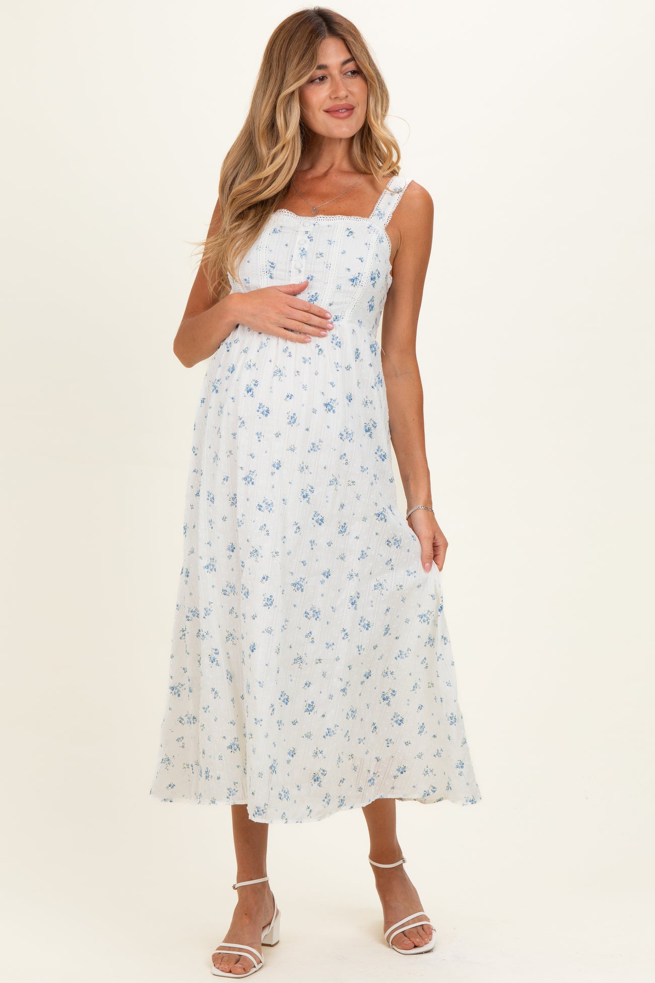 woman wearing a white floral maternity dress with adjustable straps and a baby bump visible