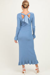 woman wearing a light blue maternity ribbed dress with a bow detail and ruffled hem, showcasing a baby bump visible from behind