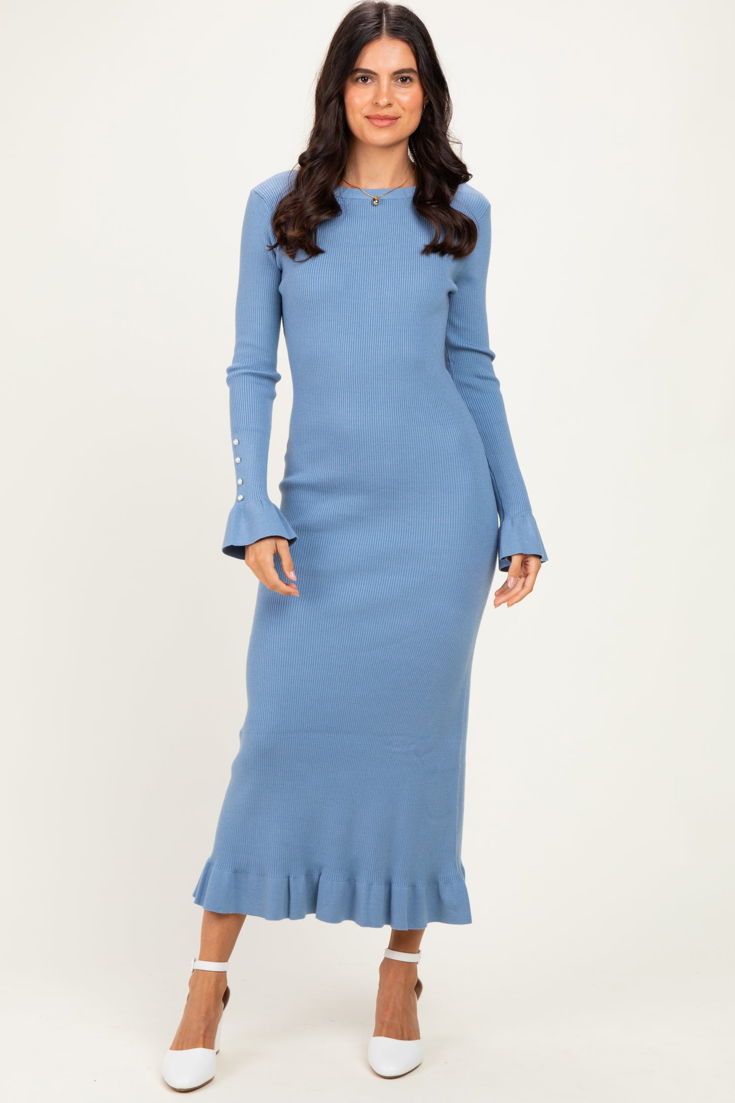 woman wearing a ribbed light blue maxi dress with flared sleeves and ruffle hem, paired with white heels