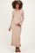 woman wearing a beige ribbed maternity dress with long sleeves, showcasing her baby bump