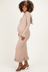 woman wearing a beige ribbed maternity dress with bell sleeves and a bow detail, showing her baby bump