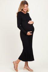 woman wearing a black ribbed long sleeve maternity dress and holding her baby bump