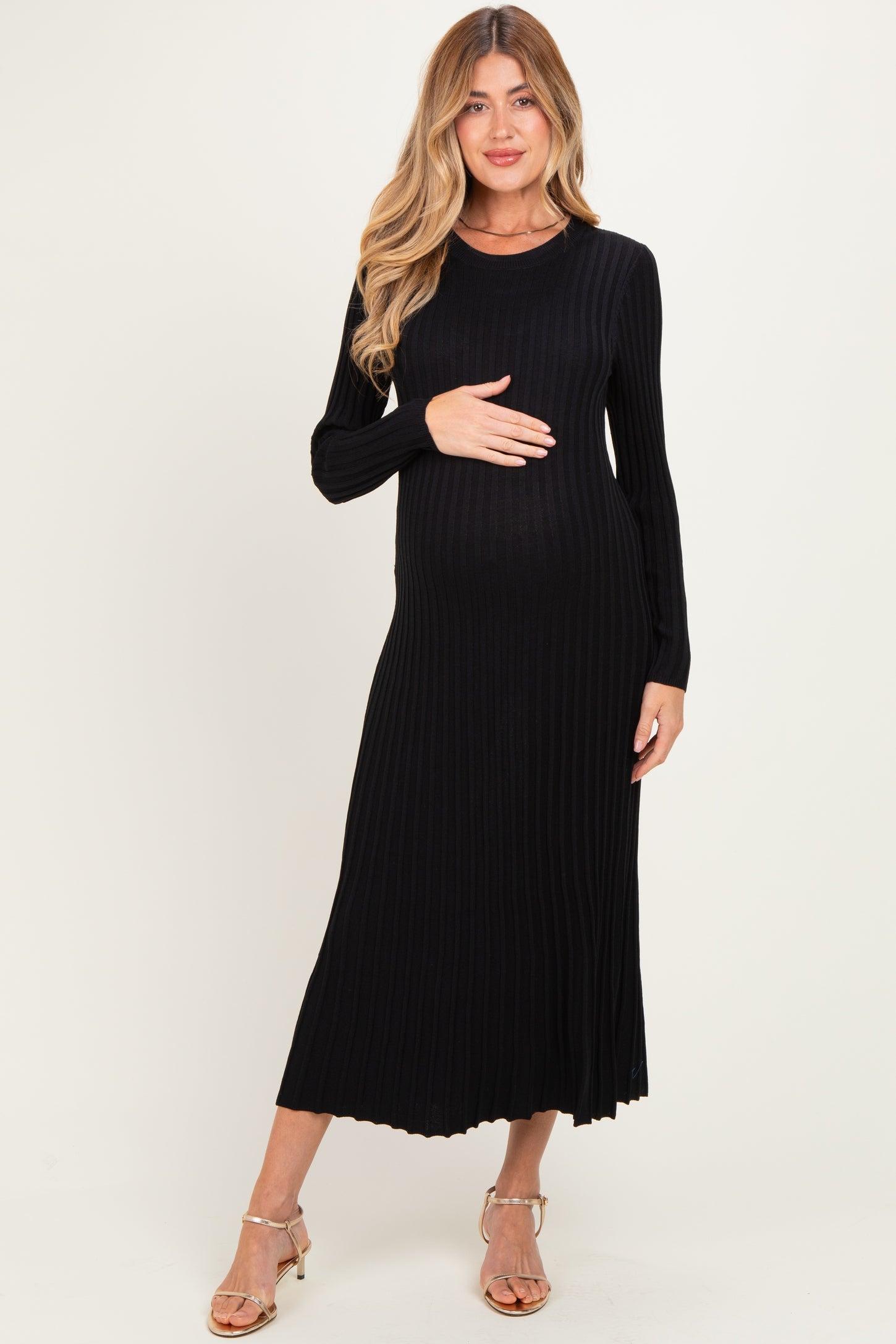 woman wearing a black ribbed long sleeve maternity dress and holding her baby bump