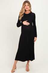 woman wearing a black ribbed long sleeve maternity dress and holding her baby bump