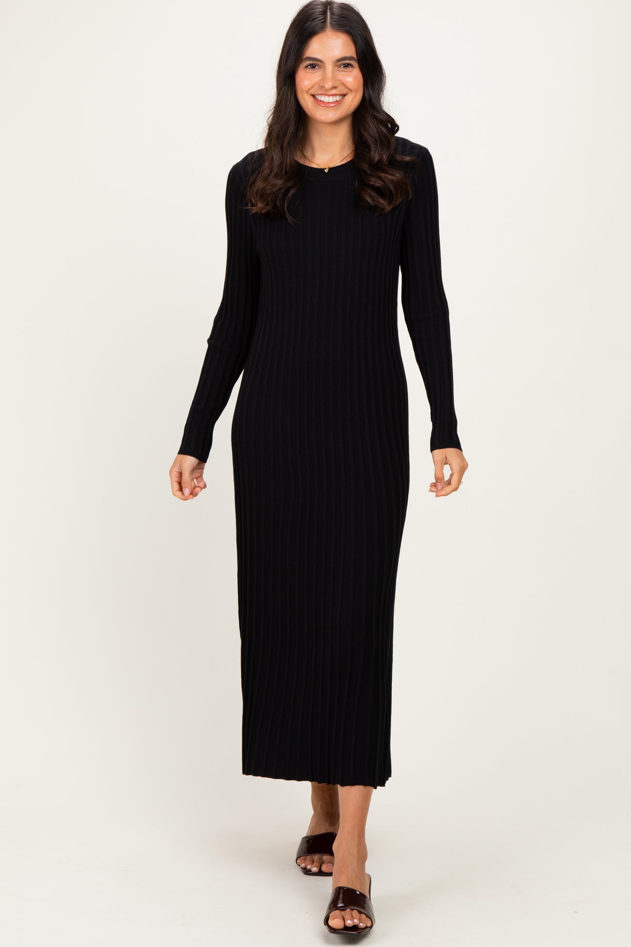 woman wearing a black ribbed long sleeve maxi dress with a fitted silhouette and slit detail at the hem