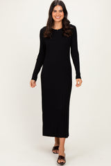 woman wearing a black ribbed long sleeve maxi dress with a fitted silhouette and slit detail at the hem