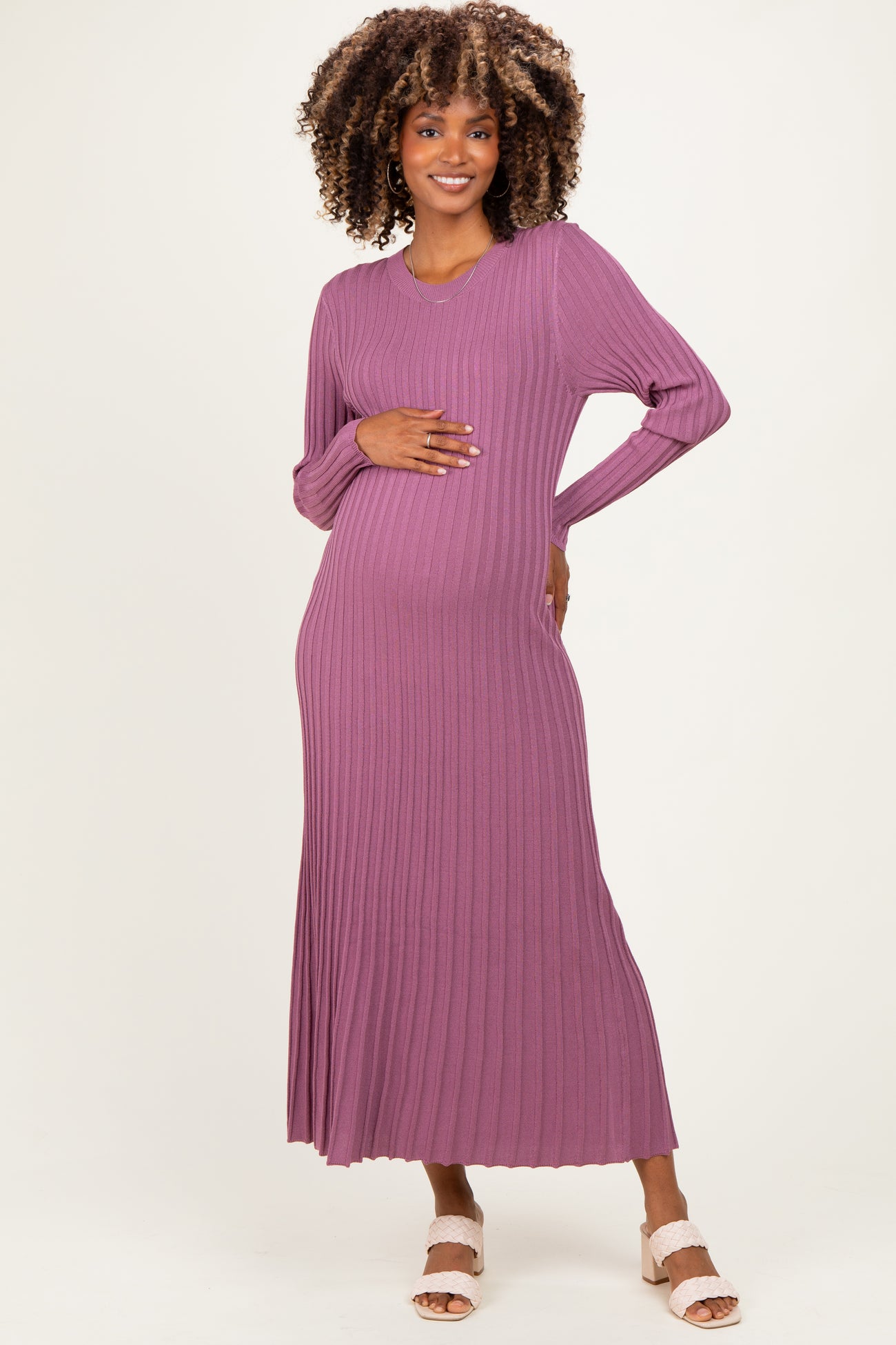 woman wearing a mauve long sleeve ribbed maternity dress, gently holding her baby bump