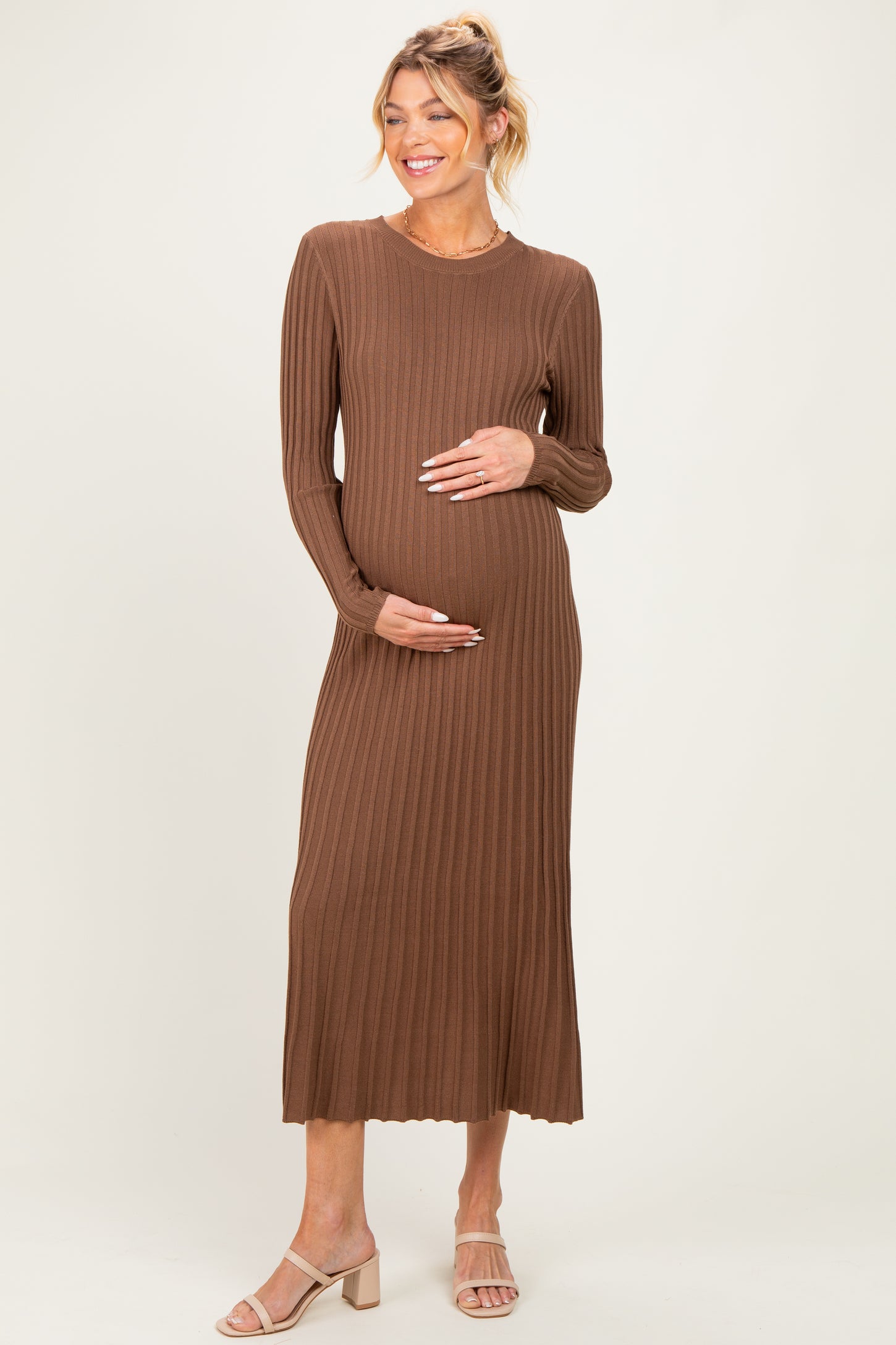 woman wearing a brown ribbed long sleeve maternity dress and holding her baby bump