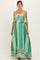 woman wearing a green strapless maxi maternity dress with a tiered design and patterned details, holding her baby bump