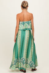 woman wearing a green patterned strapless maxi maternity dress with a flowy silhouette and a layered design