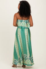 woman wearing a green patterned maxi dress with a strapless design and ruffled bodice, shown from the back