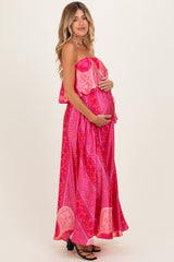 woman wearing a pink patterned maternity maxi dress and holding her baby bump